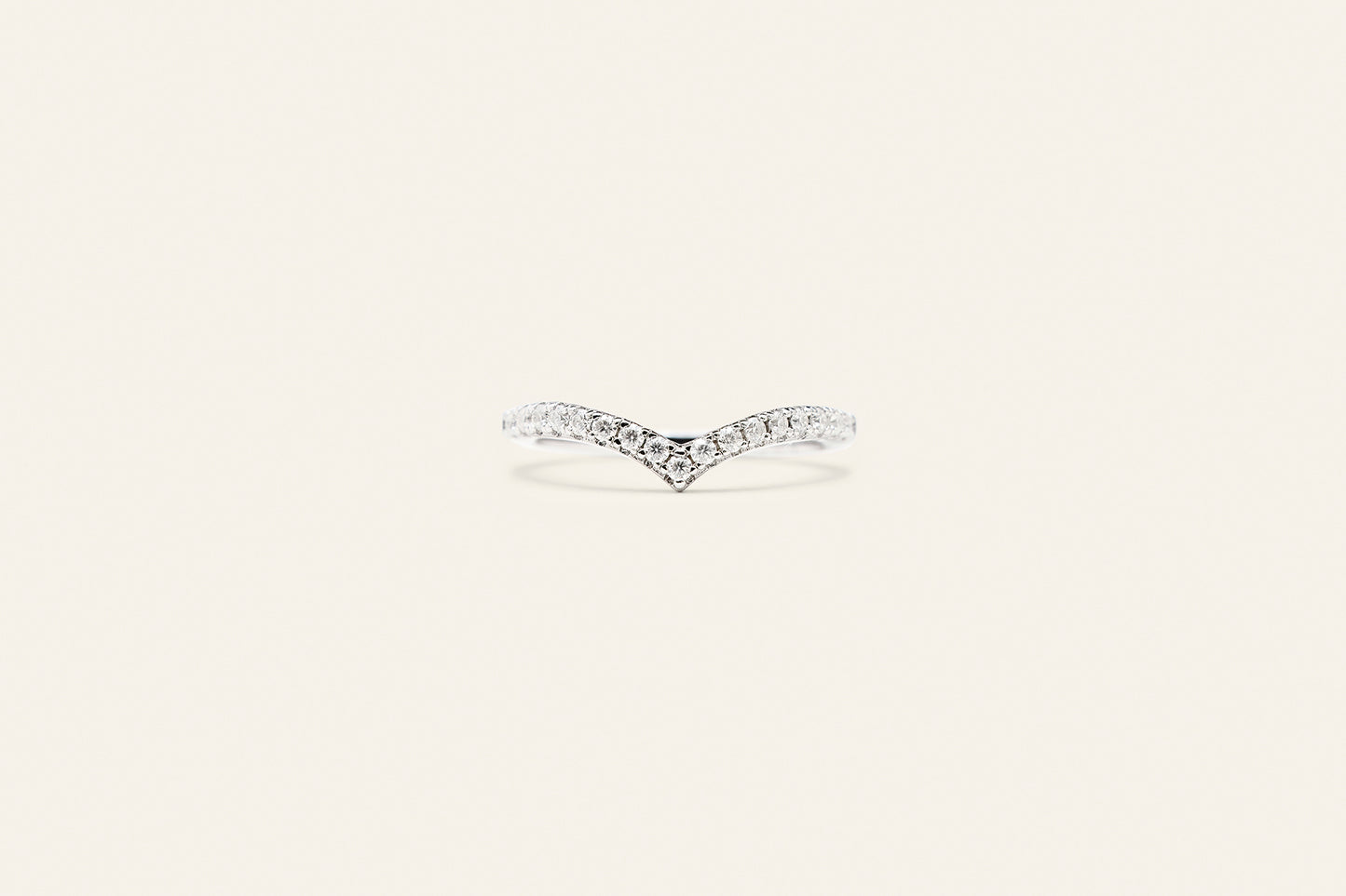 Elegant och tidlös silverring med en V-formad design. Ringen har silverstenar på framsidan och är placerad mot en ljusbeige bakgrund.