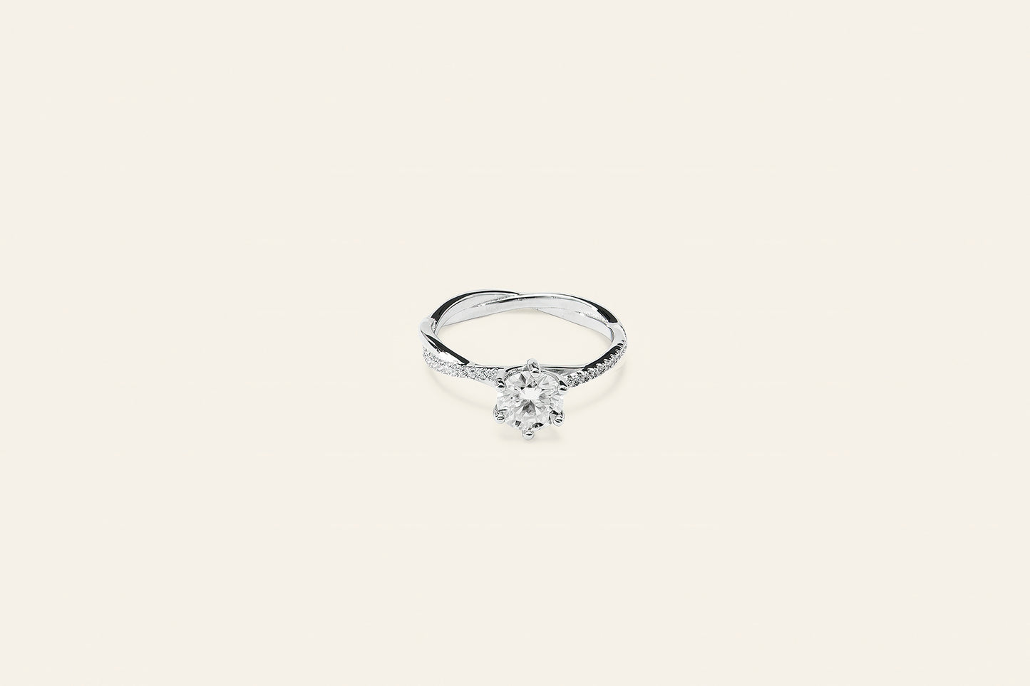 En silver solitär ring där diamanten är infattad i en klassisk sexklosfattning. Ringen har små kristaller runt om och är placerad mot en ljus bakgrund. 