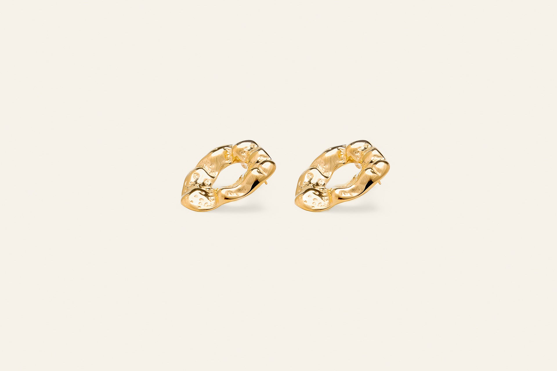 Chunky gold earrings with a molten gold design shaped as oval rings. 